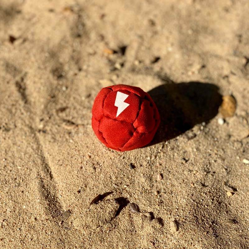 A red footbag in the sand.